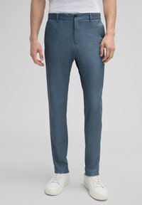 Op maat gemaakte blauwe broek van gestructureerd materiaal, met een rechte snit, zijzakken en een knoopsluiting, gecombineerd met witte sneakers.