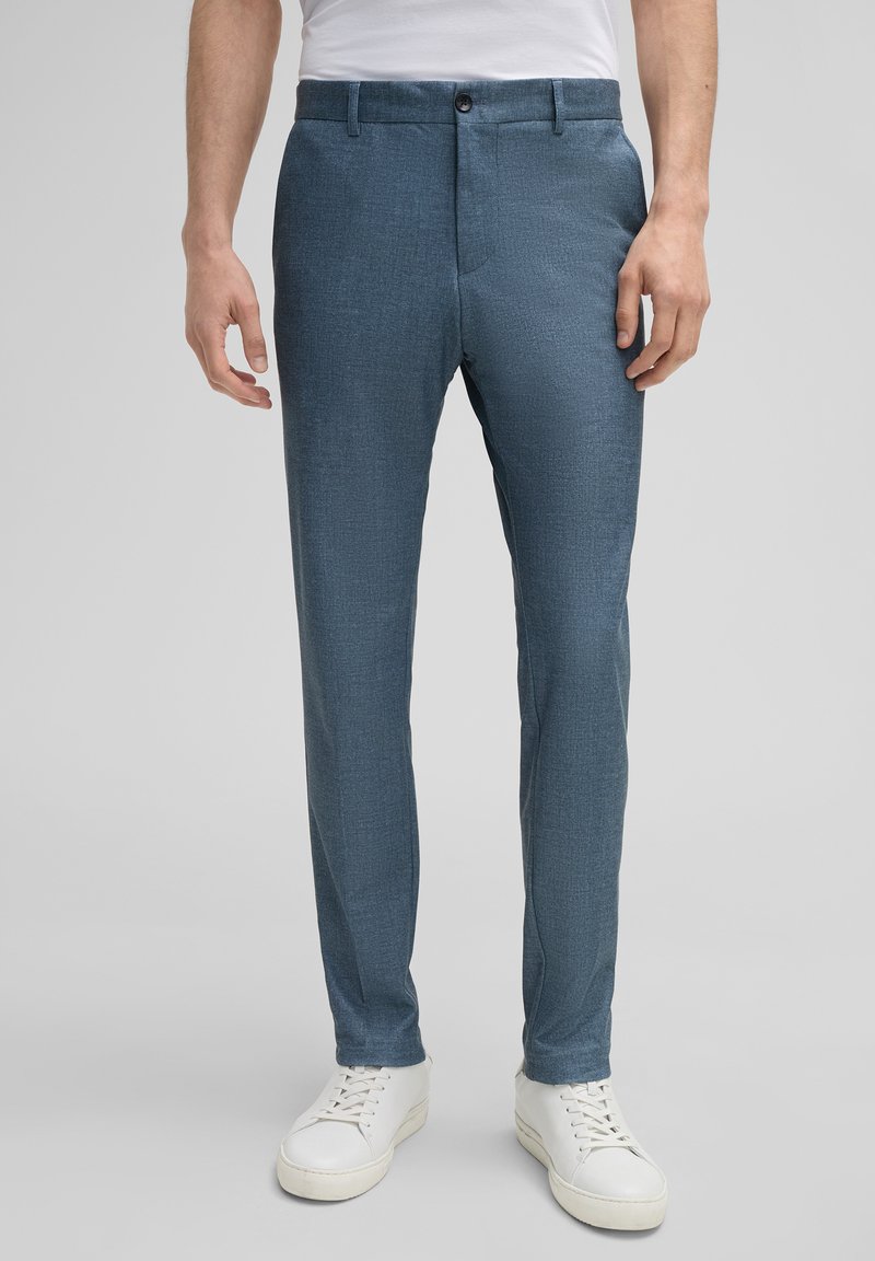 Op maat gemaakte blauwe broek van gestructureerd materiaal, met een rechte snit, zijzakken en een knoopsluiting, gecombineerd met witte sneakers.