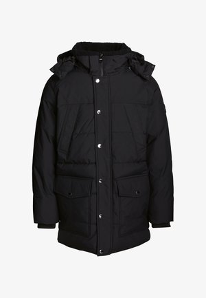 Doudoune noire avec une capuche en fausse fourrure, fermeture éclair intégrale, fermeture à pression à l'avant, deux grandes poches à rabat et poignets élastiques.