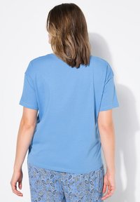 Blauwe T-shirt met korte mouwen gemaakt van zachte stof. Relaxte pasvorm met een ronde halslijn, gecombineerd met lichtblauwe broeken met een patroon.