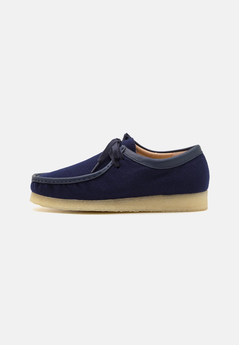 Sapatos de lã azul marinho com bico arredondado, detalhes em couro, fecho com atacadores e sola de borracha leve. Textura suave com detalhes de costura.