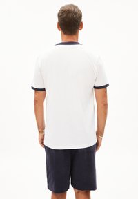 Witte T-shirt met korte mouwen en een marineblauw kraag en boorden, gecombineerd met marineblauwe shorts. De stof ziet er glad uit en heeft een ontspannen pasvorm.