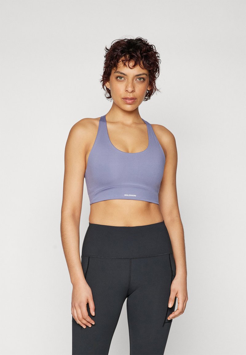Lilla sportsbh med scoop hals og brede stropper, satt sammen med høyt midje sorte tights med stikkingsdetaljer.