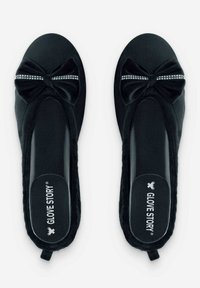 Ballerines en velours noir avec un détail en nœud accentué par une rangée de minuscules strass à l'avant. Design plat avec semelles lisses.
