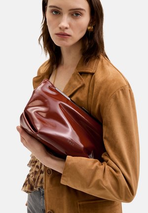 Braune Leder-Schultertasche mit glänzender Oberfläche, weichem, zerknittertem Textur und silbernem Beschlag. Der Markenname ist auf der Seite eingeprägt.