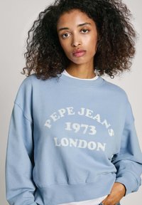 Lichtblauwe katoenen sweatshirt met "PEPE JEANS 1973 LONDON" in het wit bedrukt. Heeft een klassieke ronde hals en een relaxte pasvorm.