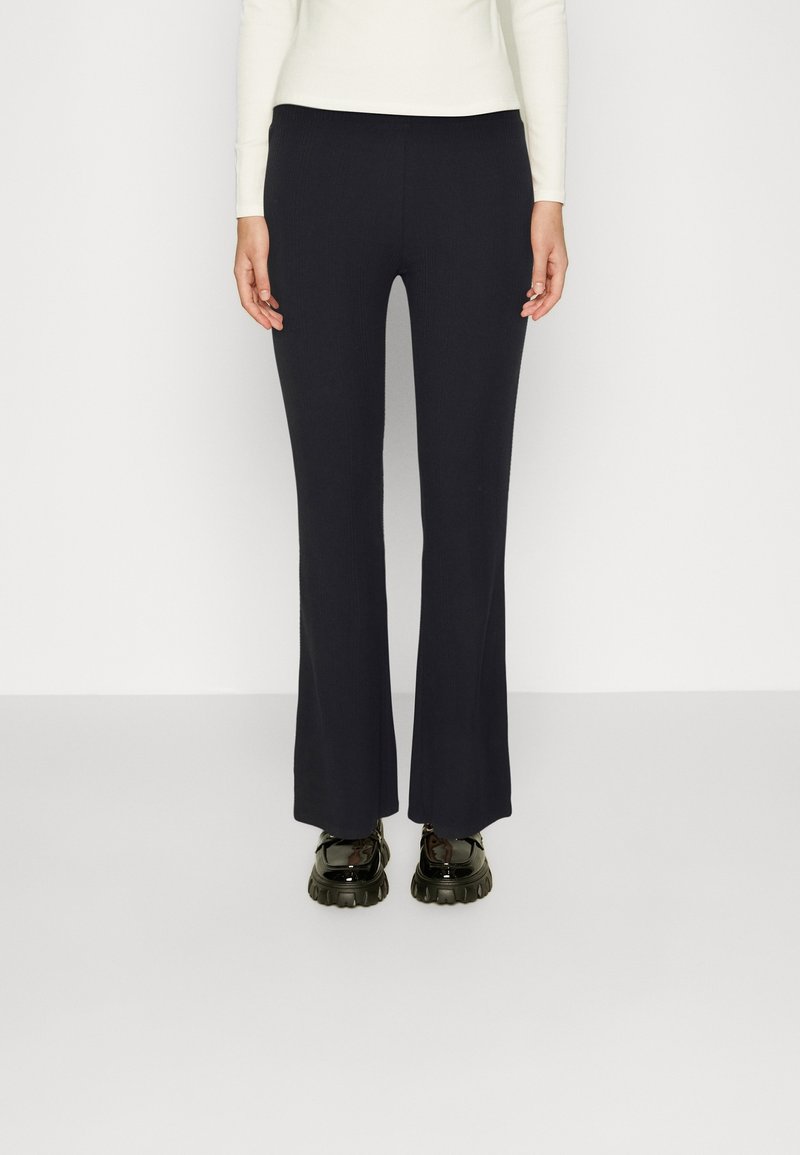 Marineblauwe geribde flared pants met een aansluitende tailleband, gecombineerd met zwarte schoenen met dikke zolen; minimalistisch ontwerp met een gladde textuur.