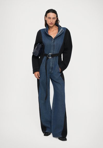 Tutina in denim con una combinazione di colori a contrasto tra nero e blu, maniche lunghe, colletto e vita con cintura. Tessuto liscio, gambe ampie.