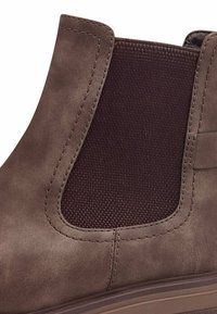 Stivaletto Chelsea marrone con tomaia in pelle liscia, pannello laterale elastico marrone scuro e finitura strutturata con cuciture visibili.