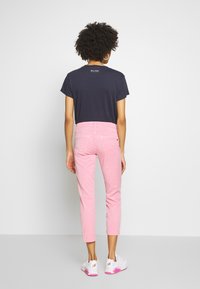 T-shirt casual bleu marine et pantalon rose court, avec une texture douce. Porté avec des baskets blanches, affichant un design simple et moderne.
