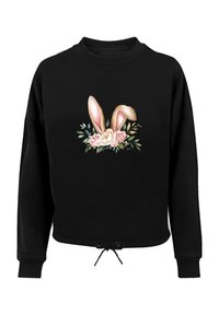 Schwarzer Pullover mit einem Grafikdesign von Hasenohren und Rosen auf der Vorderseite. Mit Kordelzug am Saum und gerippten Bündchen.