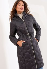 Schwarze, gestepfte Puffjacke mit Kapuze, ausgestattet mit einem Reißverschluss, verstellbarem Kordelzug in der Taille und seitlichen Taschen.