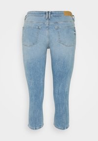 Vaqueros capri de mezclilla azul claro con un acabado desgastado, diseño de cinco bolsillos y una etiqueta de cuero marrón en la parte trasera de la cintura.