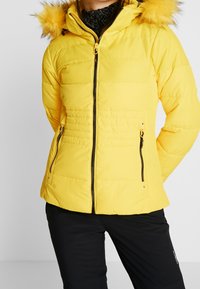 Gelbe Steppjacke mit Kapuze und Kunstfellbesatz, ausgestattet mit einem Reißverschluss vorne, seitlichen Taschen und gestepptem Design für Wärme.