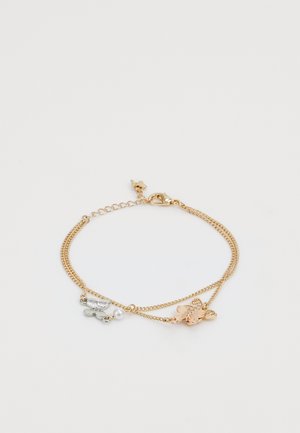 Armbånd i gull og sølv med lagdelte kjeder, en liten perle og sommerfuglecharms med teksturerte detaljer og en gribbekrok.