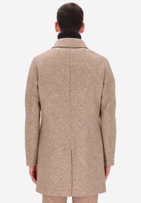 Cappotto beige a spina di pesce con collo strutturato, maniche lunghe e taglio dritto. Presenta un colletto interno a coste scuro al collo.