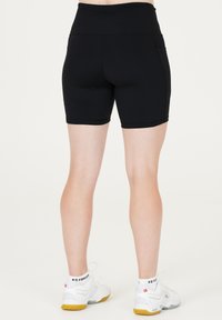 Svarta höga shorts gjorda av stretchigt tyg, med en figursydd design och längd till mitten av låret, med en slät textur och diskret ficka.