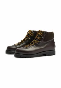 Scarpe da trekking in pelle marrone con suola robusta, lacci dorati e un morbido polsino marrone. Presentano occhielli in metallo e una finitura liscia.