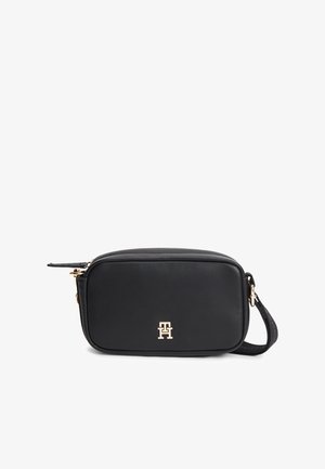 Sac bandoulière rectangulaire noir avec logo doré et bandoulière réglable, texture lisse et fermeture zippée sur le dessus.