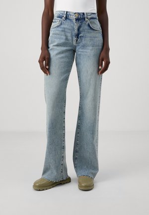 Light blue high-waisted jeans with wide legs and subtle fading. Raw edges at the hem. Paired with light olive green shoes.