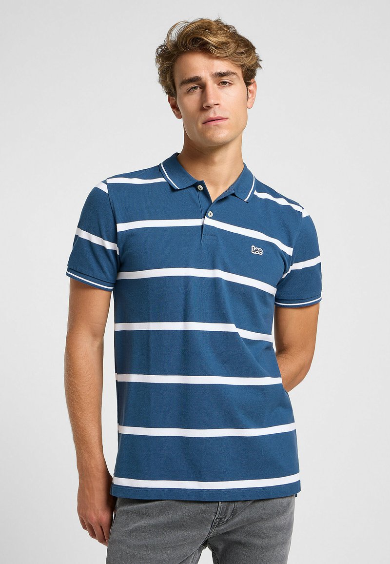 Polo a righe blu e bianche in misto cotone, con colletto a costine, patta con tre bottoni e un piccolo logo del marchio sul petto.