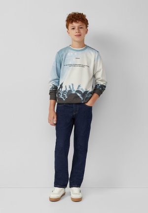 Svetlo modrý a biely grafický sweatshirt s siluetou davu, dizajn textu, rebrované manžety, v kombinácii s tmavomodrými džínsami a bielymi teniskami.