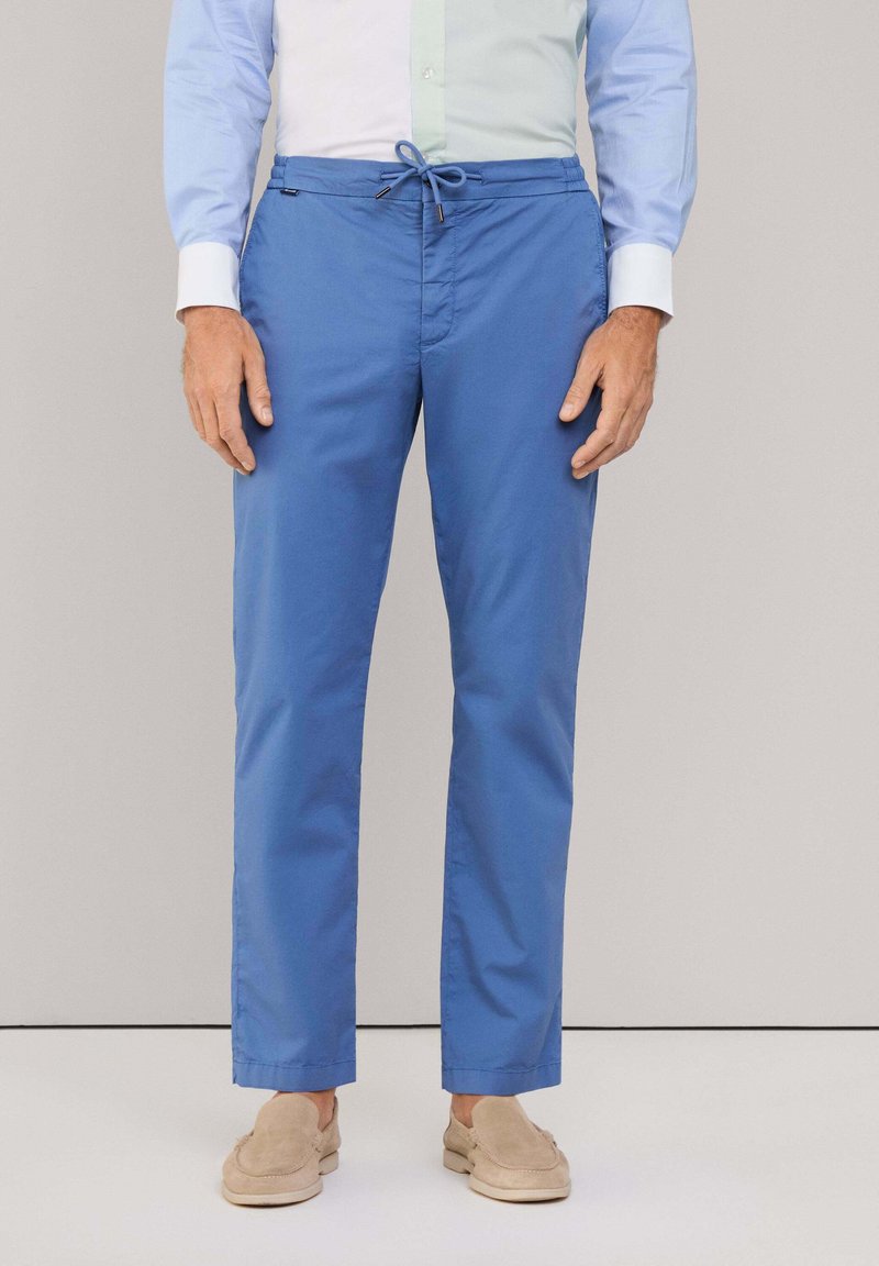 Pantaloni leggeri blu con vita elasticizzata e cordino. Tessuto liscio, taglio dritto e scarpe beige slip-on.