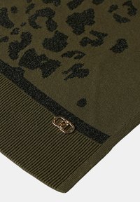 Tessuto a maglia verde oliva con macchie leopardate nere e orlo a costine, con una piccola fibbia logo in metallo dorato vicino al bordo.