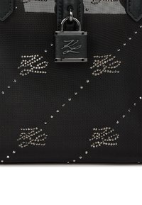 Czarna torebka teksturowana z metalowymi elementami i zamkiem. Udekorowana błyszczącymi wzorami, o zorganizowanej formie i mocnych uchwytach.