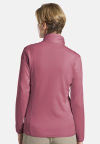 Chemise à manches longues en mauve avec un col haut, motif texturé et finition lisse, présentée de dos.