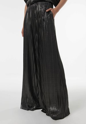 Zwarte geplooide wijde broek met een glanzende, gestructureerde oppervlakte en een elastische tailleband. Zakken zichtbaar aan de zijkanten.