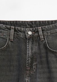 Black denim jeans with a regular waistband, silver button closure, and contrasting stitching. Features five pockets and a sturdy texture.