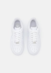 White leather sneakers with round toe, padded collar, and flat lace-up design. Features perforations on the toe box and silver branding accents.