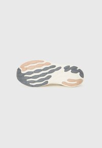 Sål af en sneaker med et bølget design i creme, grå og lyserød. Tekstureret gummi for greb og holdbarhed.