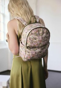 Rucksack mit Blumenmuster in Pastellrosa und Grün, mit runder Form, Stoffreißverschluss und gepolsterten Trägern für Komfort.