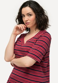 Rood en marineblauw gestreept V-hals t-shirt met korte mouwen. De stof lijkt zacht met een losse pasvorm en subtiele textuur.