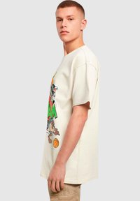 Cremefarvet bomulds t-shirt med en løs pasform, der har et farverigt Looney Tunes grafisk design og korte ærmer.