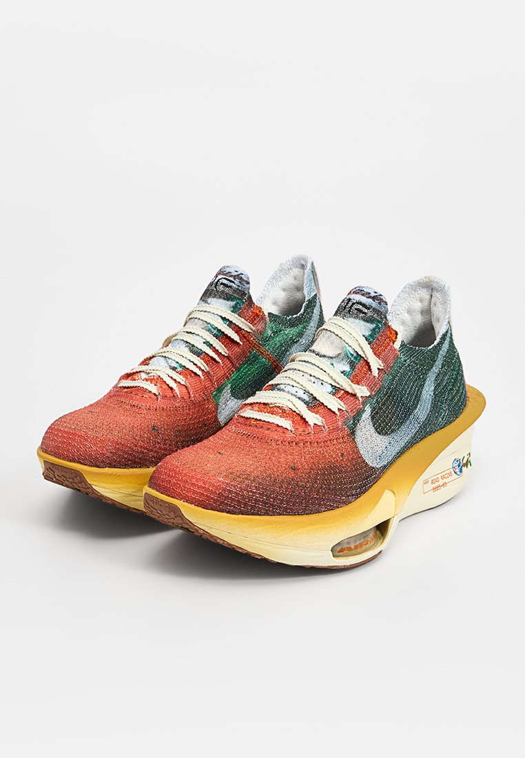 Chaussures de course Nike avec une tige en maille dégradée rouge, verte et bleue, des lacets blancs, et une semelle intermédiaire jaune avec une unité d'air visible.