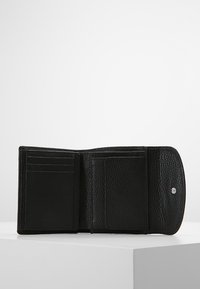 Il portafoglio in pelle nera presenta numerose fessure per carte, una finitura testurizzata e una chiusura a scatto. L'interno include sezioni per l'organizzazione.