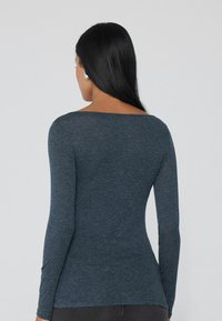 Lang�ärmliges, marineblaues Hemd aus einem weichen, strukturierten Stoff. Es hat einen weiten Halsausschnitt und eine figurbetonte Silhouette, ohne sichtbare Muster oder Akzente.