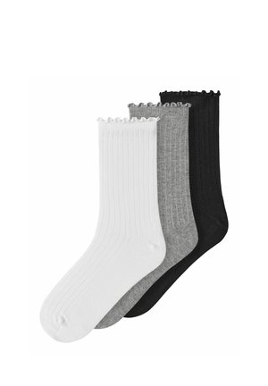 Trois paires de chaussettes courtes côtelées avec bords ondulés en blanc, gris et noir, empilées côte à côte sur un fond blanc.