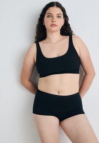 Svart bh och högmidjade shorts i mjukt och stretchigt tyg. Har en rundad halsringning och slät midjeband.
