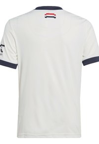 Maillot de sport blanc avec un col et des manches bleu marine. Présente une marque sur la manche gauche et une étiquette au dos du col.