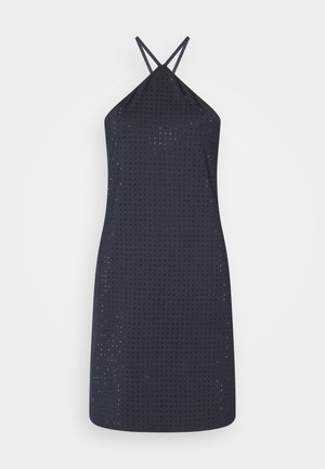 Robe noire sans manches avec petits trous perforés partout et fines bretelles croisées sur un fond blanc.