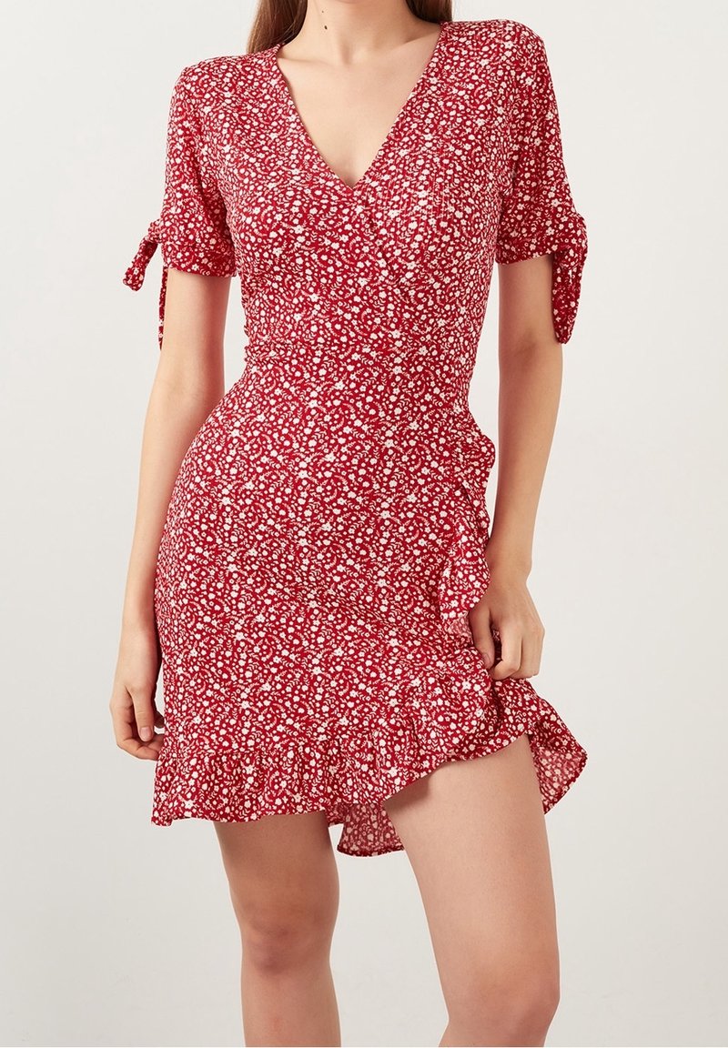 Robe florale rouge à manches courtes, col en V, boutons et ourlet volanté. Fabriquée en tissu léger avec une texture agréable et des accents de nœuds.