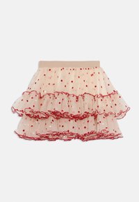 Jupe en tulle nude avec des pois rouges, présentant trois couches de volants et une bordure froncée rouge le long de l'ourlet et de la taille.
