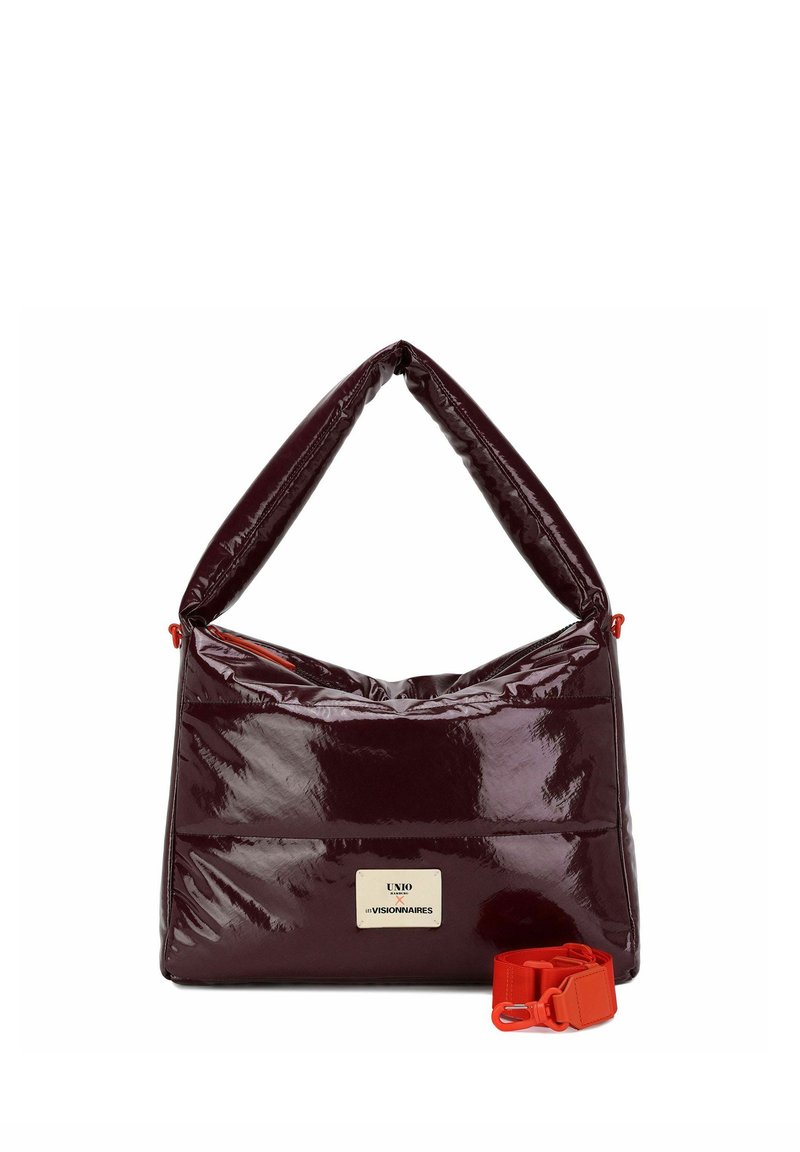 Bolso de mano de cuero charol burdeos con acabado brillante, diseño acolchado y una correa roja ajustable. Cuenta con una placa con el logo en el frente.