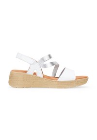Las sandalias blancas de cuña presentan una tira plateada texturizada, un diseño de punta abierta y una suela tejida estilo espadrille que aporta altura y comodidad.