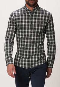 Svart- och vitrutig skjorta med krage, med långa ärmar och en figurnära design. Texturerad tyg med varierade mönster.