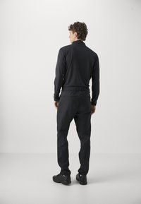 Black long-sleeve shirt and matching pants, featuring a relaxed fit, elastic waistband, and smooth texture. Minimalist design and no visible logos.